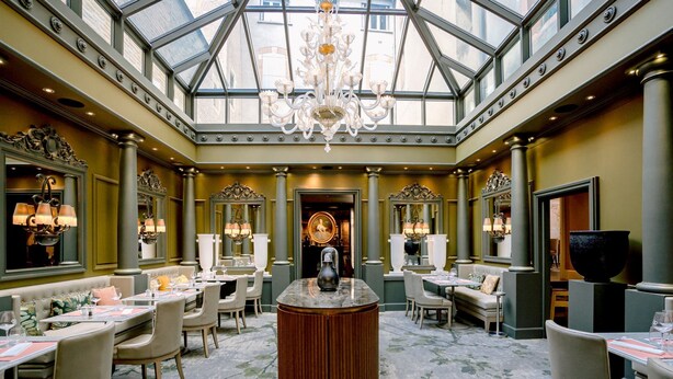 A luxurious dining area with a central bar, high ceilings, and ornate chandeliers.