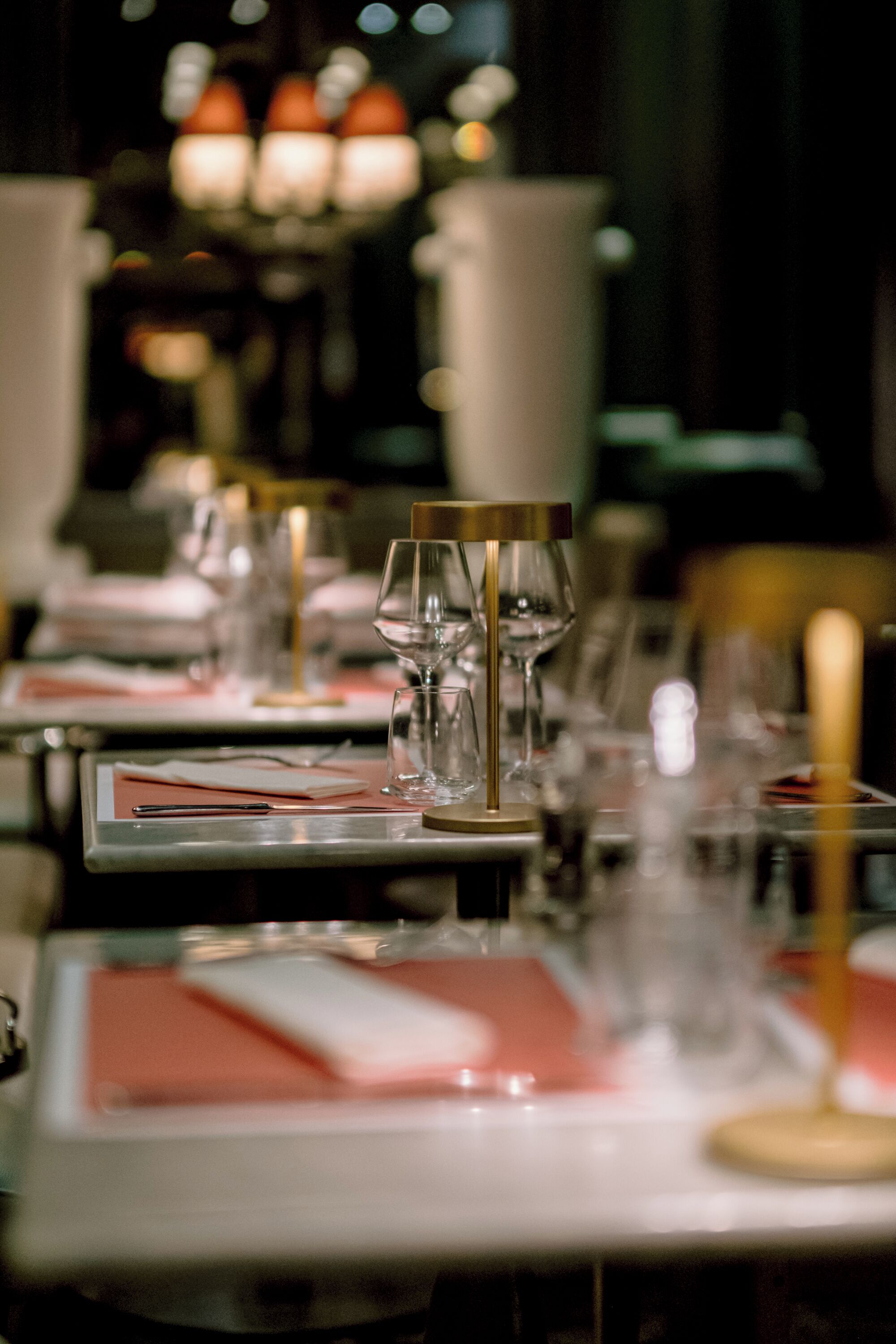A dining table set with wine glasses, plates, and cutlery, with a candle holder and a vase in the center.