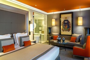 A hotel room with a bed, a sofa, a coffee table, and a bathroom visible through a glass door. - Alchimy (Albi)