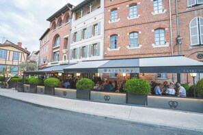 A restaurant with outdoor seating, a sign reading "Alchimie hotel", and brick buildings in the background. - Alchimy (Albi)