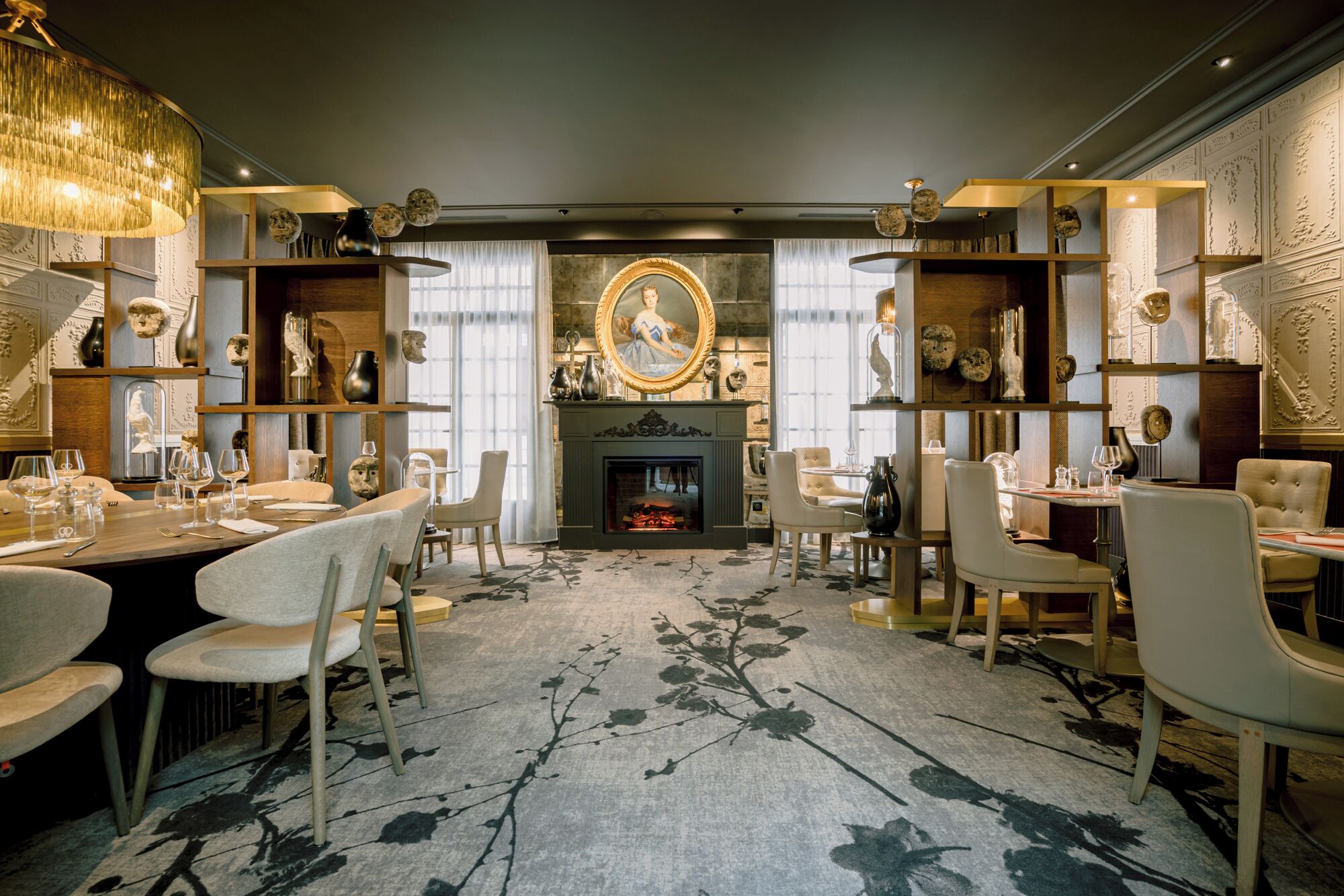 A dining room with a fireplace, ornate shelves, and a chandelier.