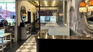 A modern hotel lobby with a check-in counter, a bar area with liquor bottles, a large mirror, and a tiled floor.