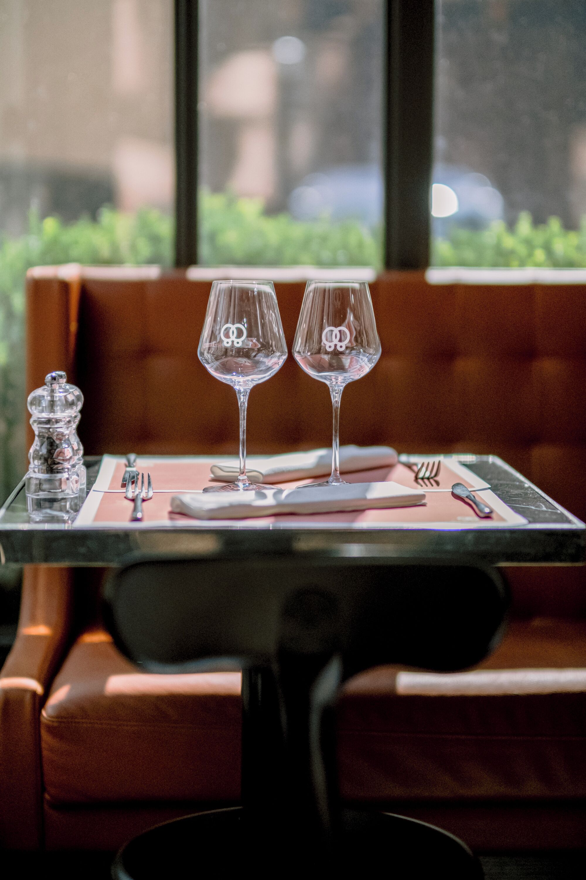 A table with two wine glasses and a salt and pepper shaker, set on a pink placemat.