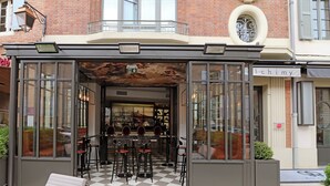 A café with outdoor seating, a checkered floor, and a brick building facade.