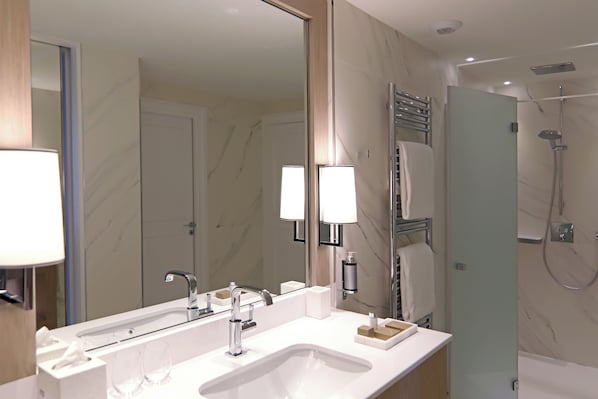 Un baño moderno con tocador doble lavamanos, un espejo grande y zona de ducha.