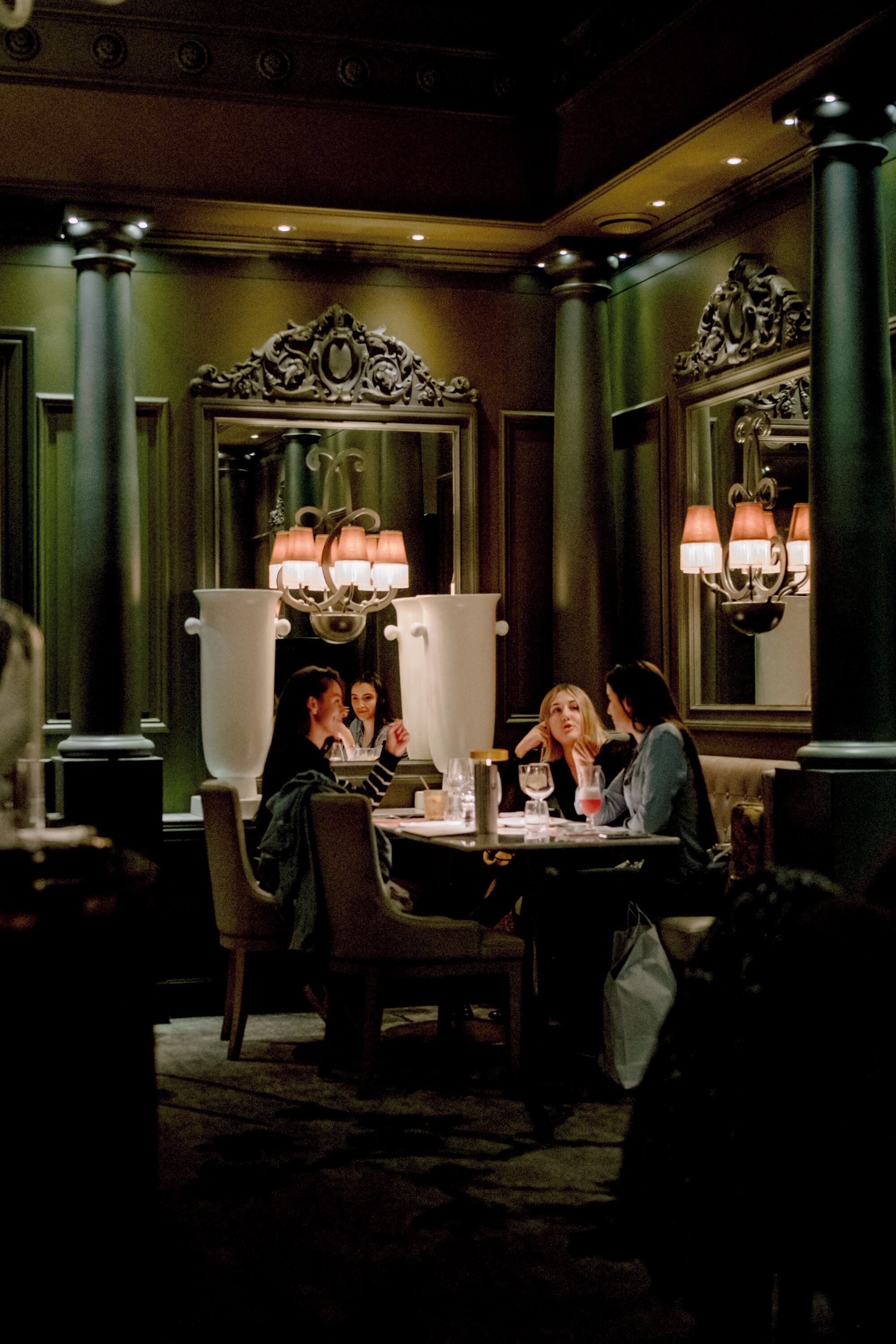 A dimly lit restaurant with ornate decor, including a large mirror and decorative columns.