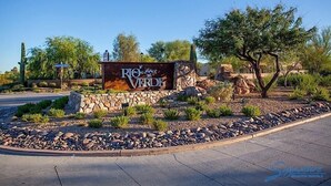 A sign for Rio Verde with a stone wall and landscaping. - Rio Verde Townhouse By Signature Rentals (Rio Verde)
