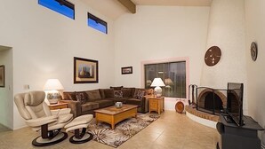 A living room with a sofa, armchairs, a coffee table, a fireplace, and a TV. - Rio Verde Townhouse By Signature Rentals (Rio Verde)