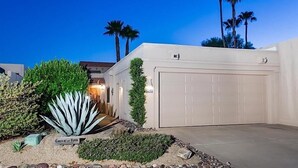 A modern house with a garage, surrounded by well-maintained landscaping and palm trees. - Rio Verde Townhouse By Signature Rentals (Rio Verde)