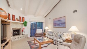 A living room with a fireplace, a sofa, a coffee table, and a painting on the wall.