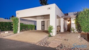 A modern house with a covered driveway, a well-maintained lawn, and a palm tree in the background.