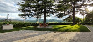 Un jardín paisajístico con una zona de estar, un asta de banderas y vistas a colinas distantes.