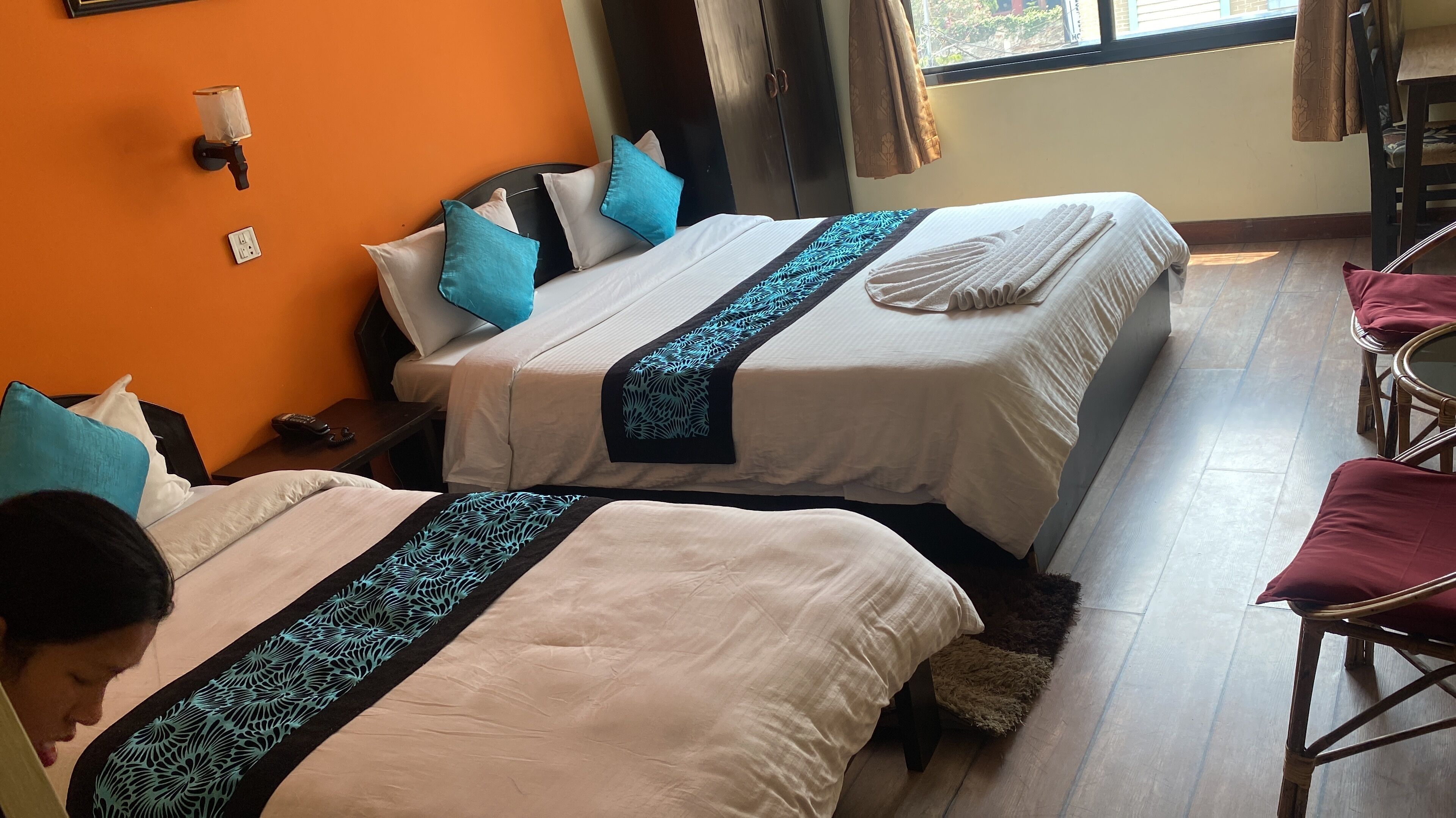 A hotel room with two beds, a small table, and a chair.