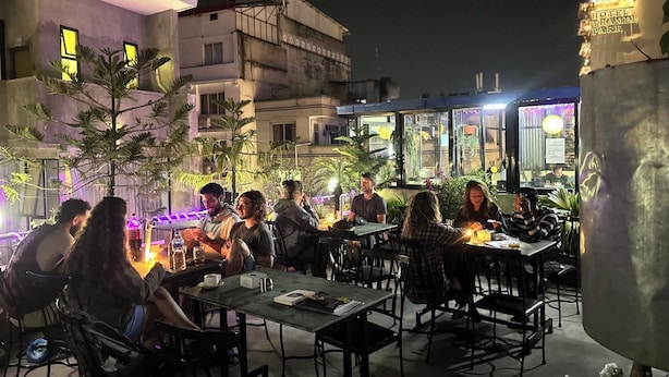 An outdoor dining area with tables and chairs, surrounded by buildings and plants. - Bag Packer's Lodge (Kathmandu)
