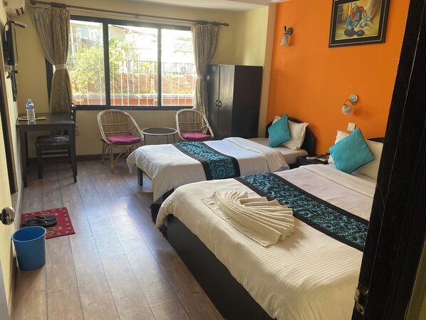 A hotel room with two beds, a desk, chairs, a wardrobe, and a view of the outside. - Bag Packer's Lodge (Kathmandu)