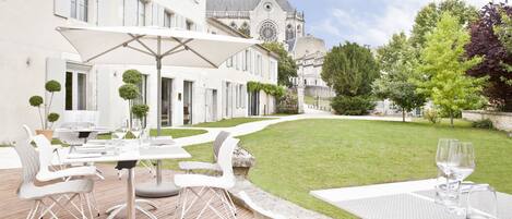 A courtyard with outdoor seating, a church in the background, and a well-maintained lawn.