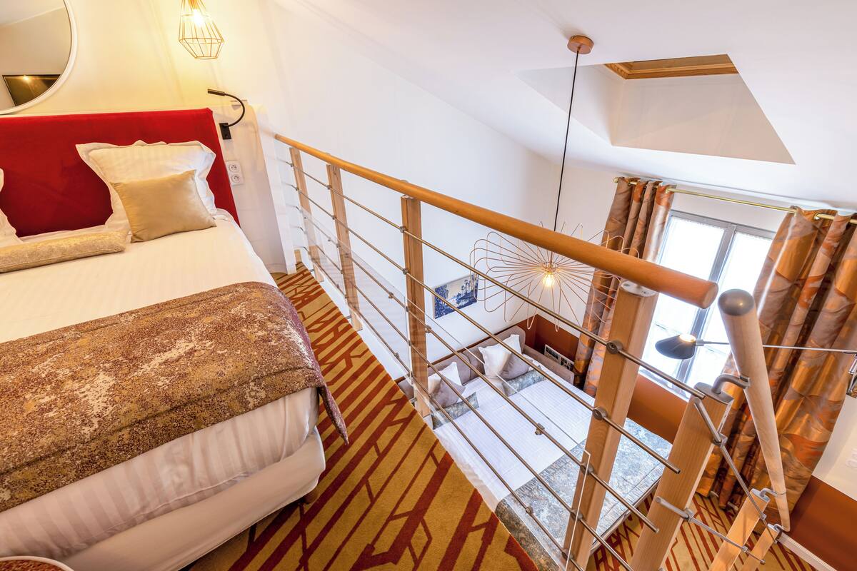 A high-ceilinged room with a bed, a red headboard, and a patterned carpet.