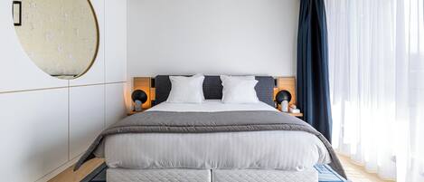 Un dormitorio moderno con una cama grande, un espejo redondo y un techo con diseños intrincados.