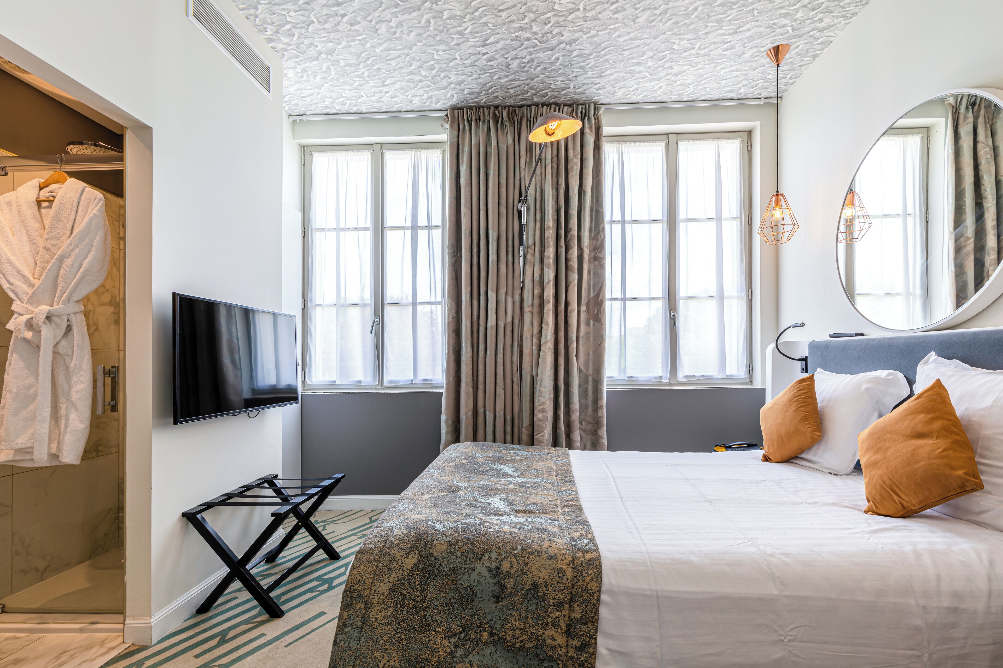 Een hotelkamer met een bed, een televisie, een grote spiegel en een raam met gordijnen.