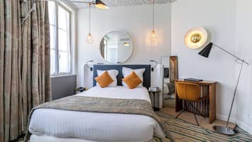 Una habitación de hotel con una cama grande, un escritorio, una silla, un espejo y una lámpara.