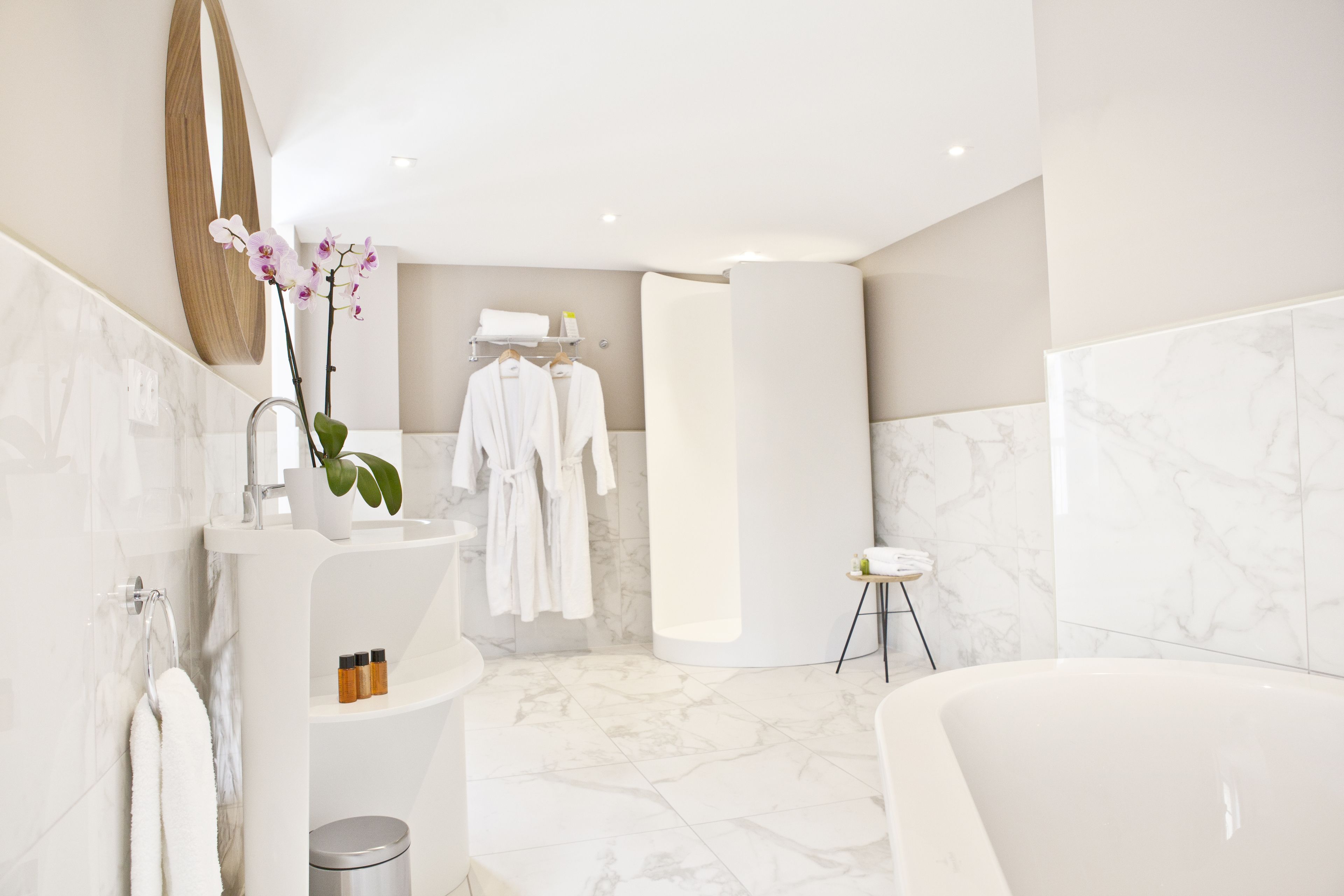 A modern bathroom with a marble floor, a bathtub, a sink with a mirror, and a shower area.