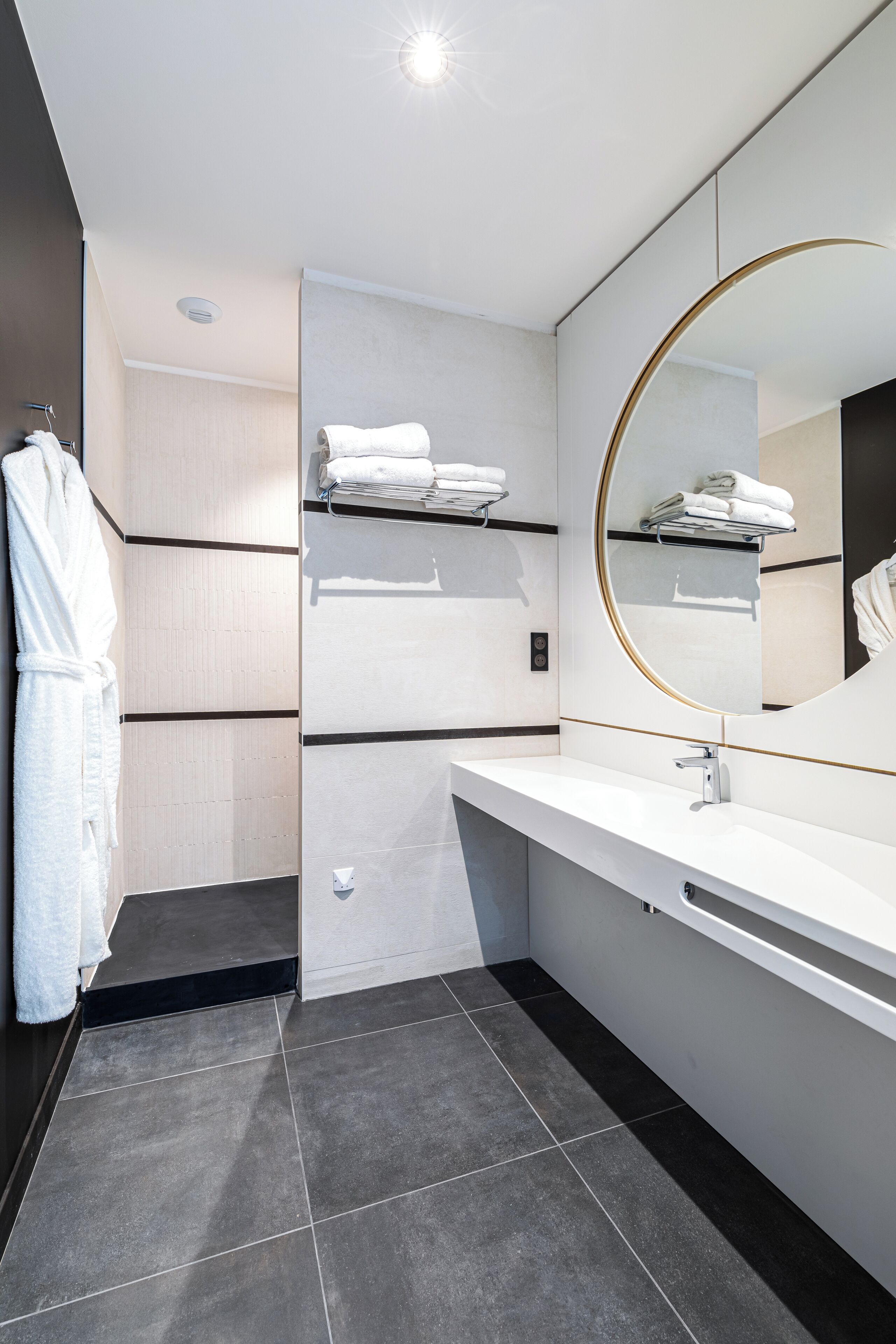 Un baño moderno con un tocador blanco, un espejo grande y un perchero para toallas.