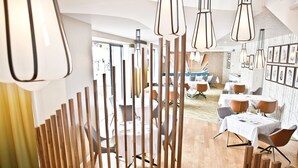 Un espace de restauration moderne avec des cloisons en bois, des tables blanches et des luminaires contemporains.