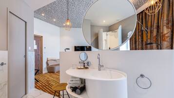 A modern bathroom with a large mirror, a white sink, and a towel rack.