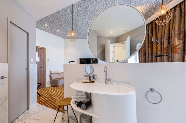 A modern bathroom with a large mirror, a white sink, and a towel rack. - Hotel Angoulême Le Saint Gelais (Angouleme)
