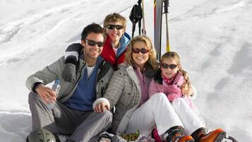 A group of people sitting on the snow with skis and ski poles beside them.