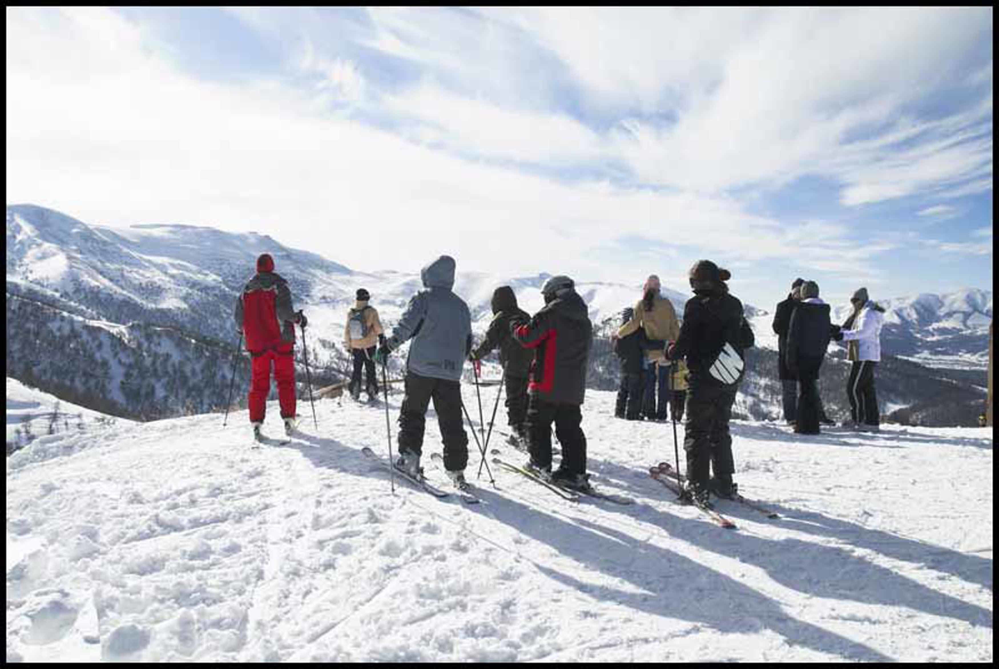 A group of people on a snowy mountain with a clear sky.