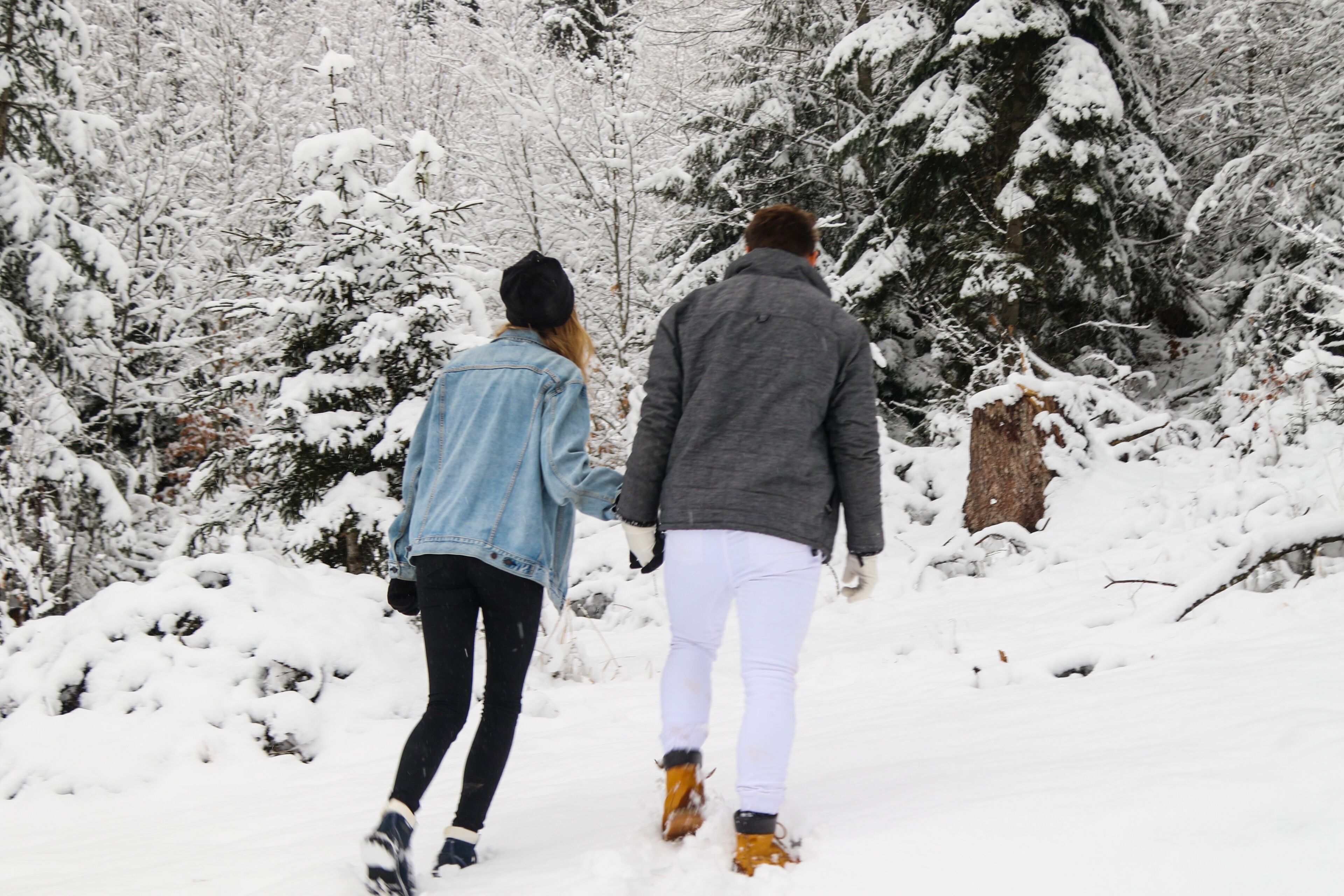 Dos personas caminando por un sendero cubierto de nieve, rodeado de árboles.