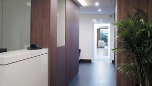 Un área de recepción moderna con un mostrador, una planta en maceta y vistas al interior.