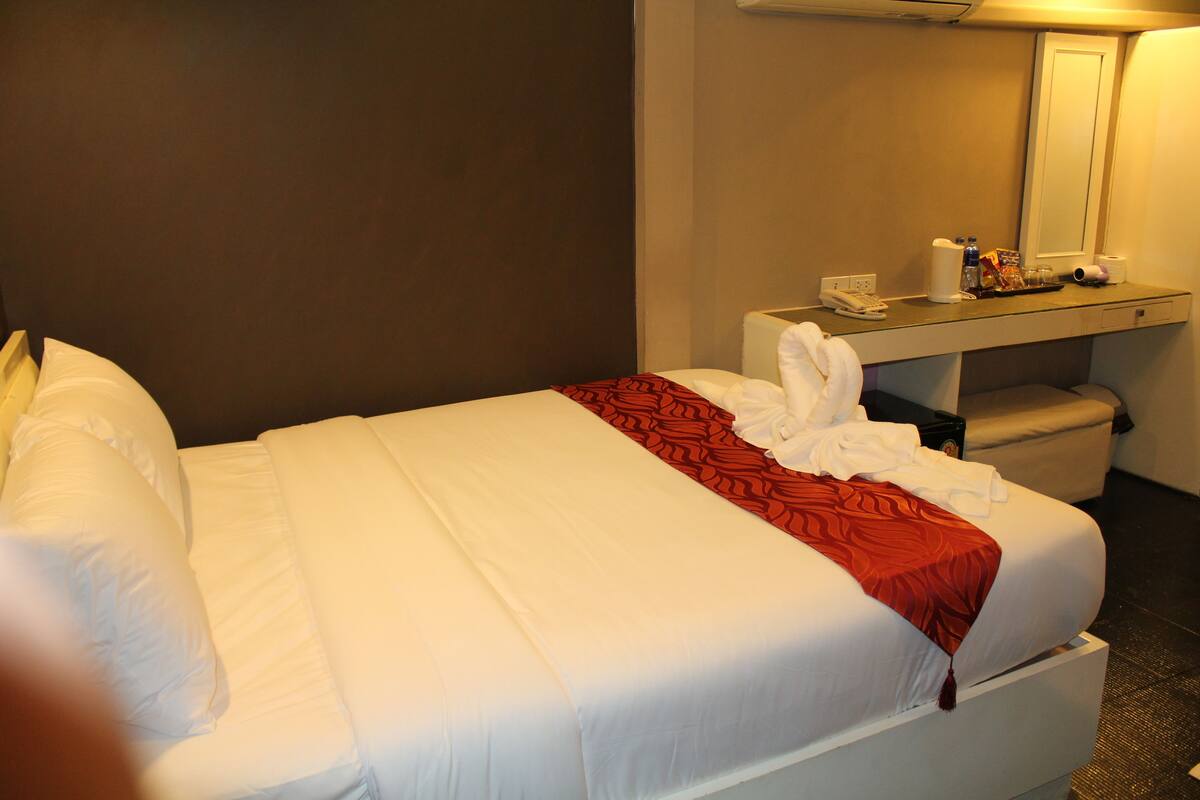 Une chambre d’hôtel comprenant un lit, une table de chevet avec un téléphone, un miroir et un petit coin salon.