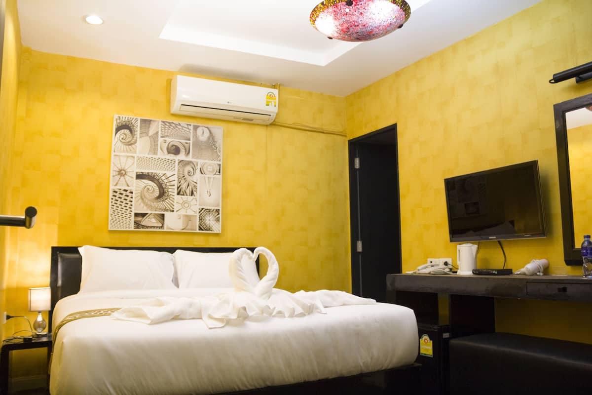 Une chambre d’hôtel équipée d’un lit, d’un climatiseur fixé au mur, d’un téléviseur à écran plat et d’un miroir.