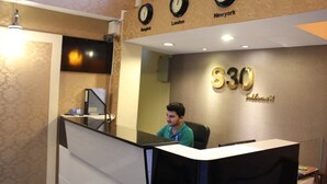 A reception desk with a clock above it displaying times for Bangkok, London, and New York. The wall behind the desk has a sign with '$30' and 'Sublimax'. - S30 Sukhumvit Hotel (Bangkok)