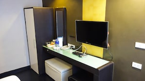 A compact hotel room with a kitchenette, a flat-screen TV, a desk with a phone and remote, and a small seating area. - S30 Sukhumvit Hotel (Bangkok)