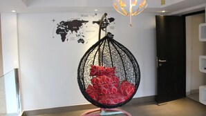 A room with a hanging chair with red patterned cushions, a world map on the wall, and a globe light fixture. - S30 Sukhumvit Hotel (Bangkok)