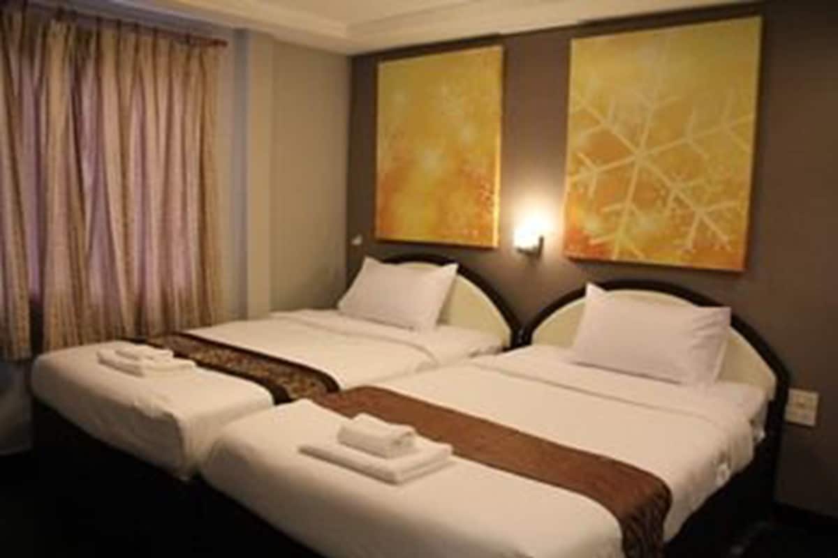 Une chambre d’hôtel avec deux lits, une fenêtre avec des rideaux et deux tableaux abstraits accrochés au mur.
