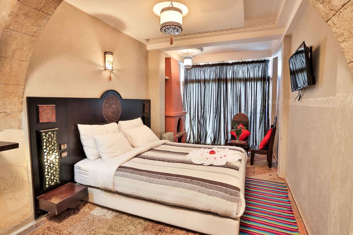 A hotel room with a large bed, a flat-screen TV mounted on the wall, and a decorative wall panel.