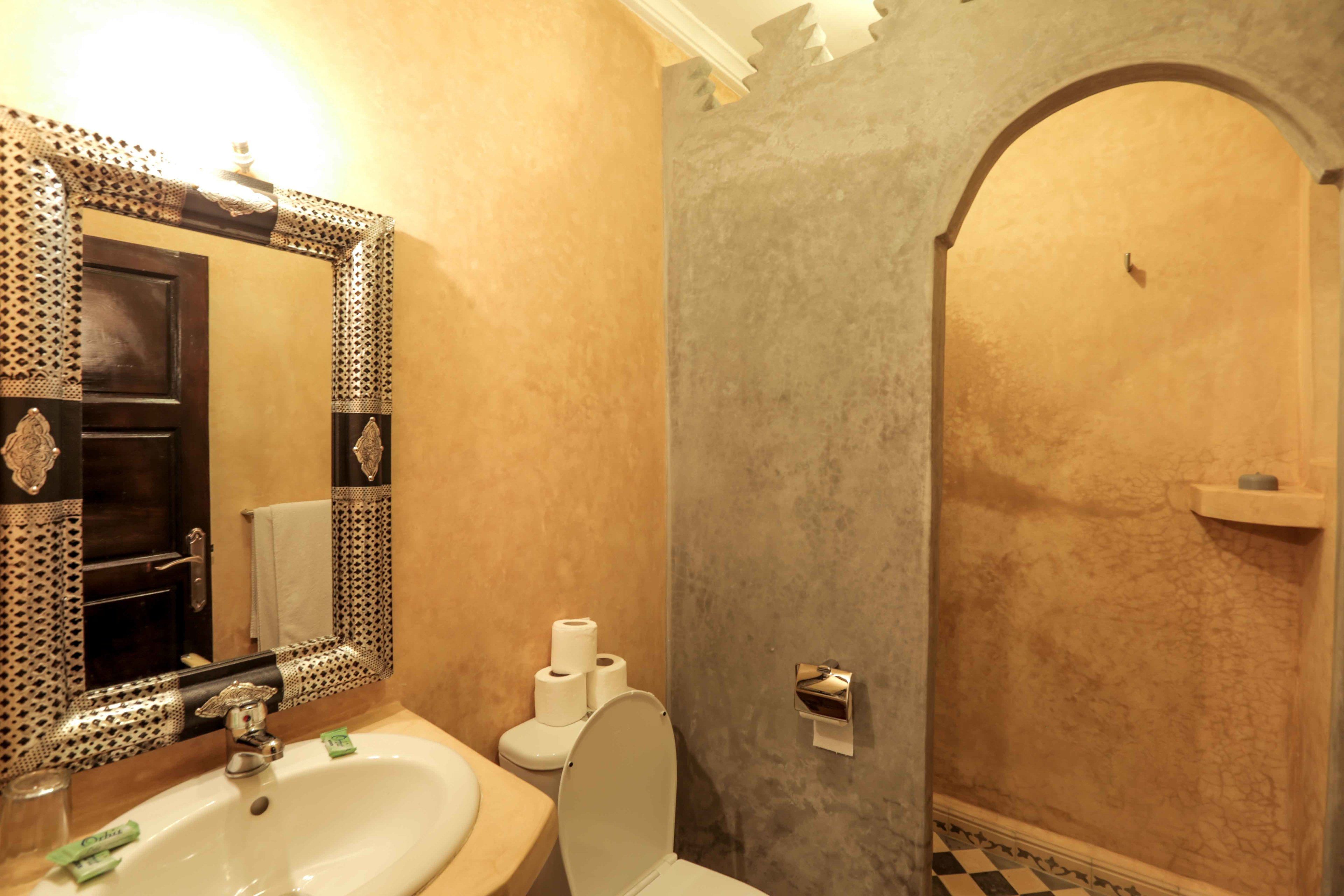 A bathroom with a sink, toilet, and mirror.