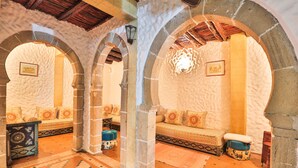A traditional interior with stone arches, a patterned sofa, and a tiled floor. - Riad Nakhla (Essaouira)