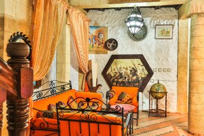 Una habitación con una cama, cortinas naranjas, un globo terráqueo y decoración en la pared.