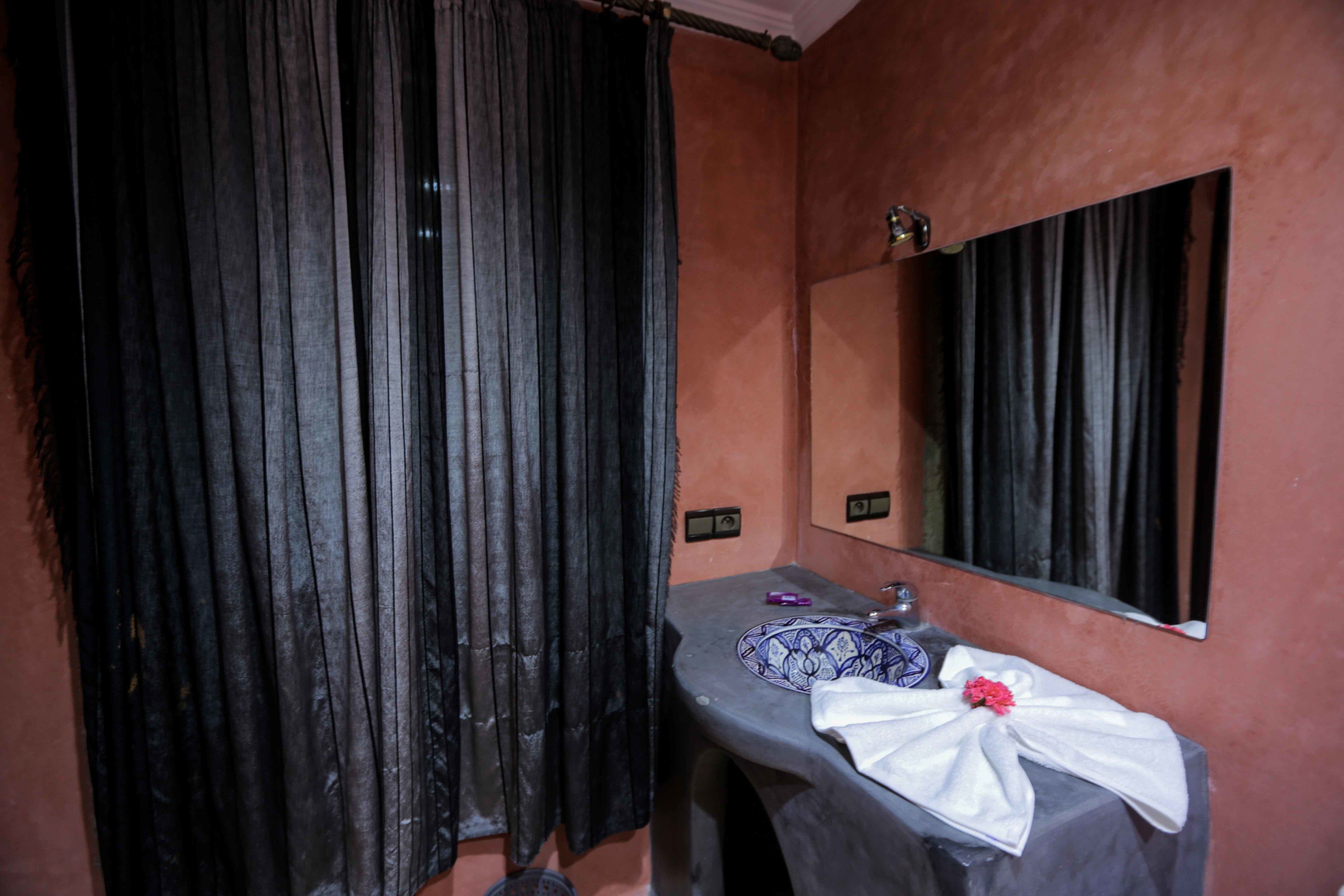 A bathroom with a sink, mirror, and dark curtains.