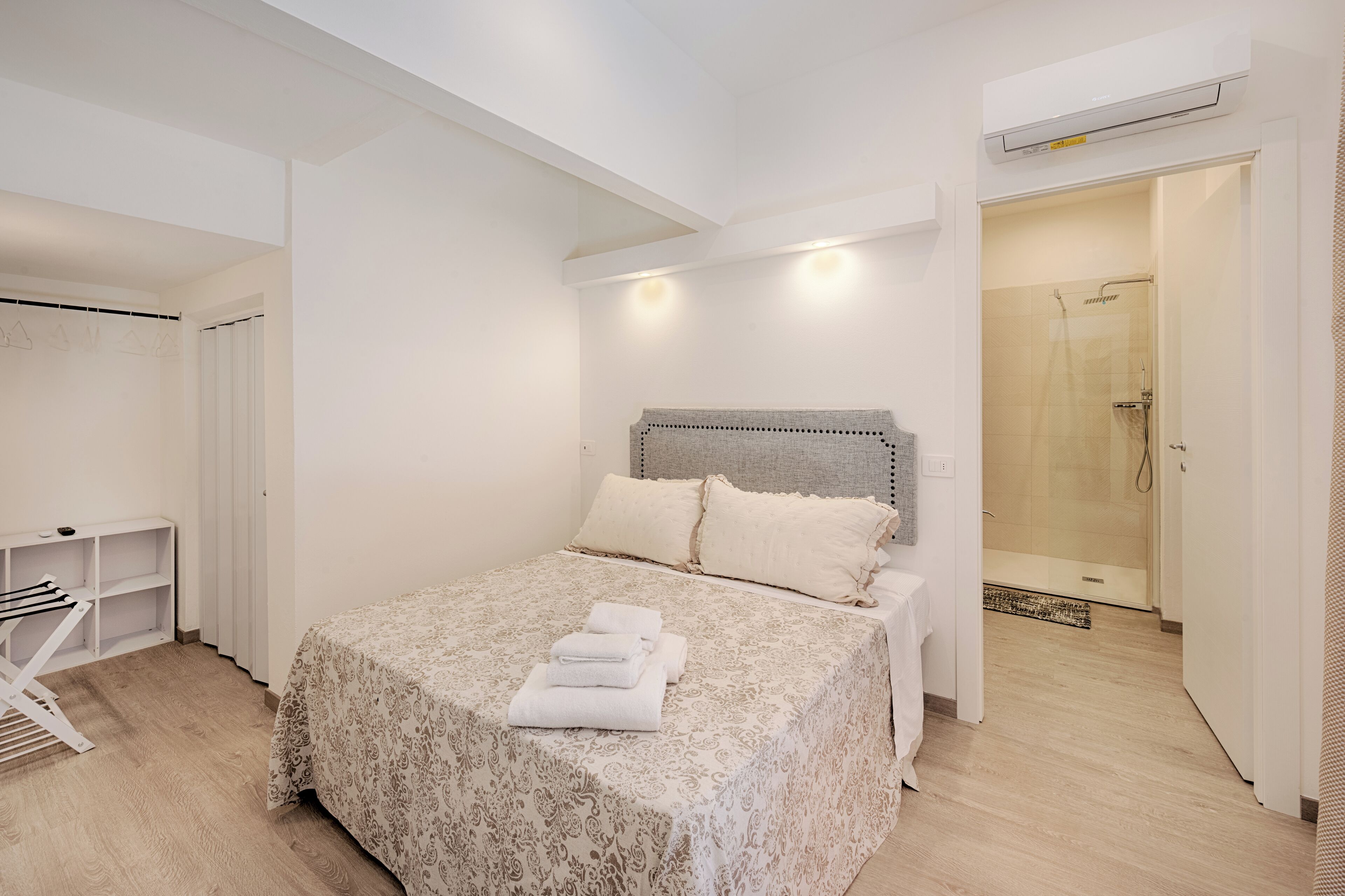 Ein Schlafzimmer mit Bett, Nachttisch, Kleiderschrank und Duschbereich.