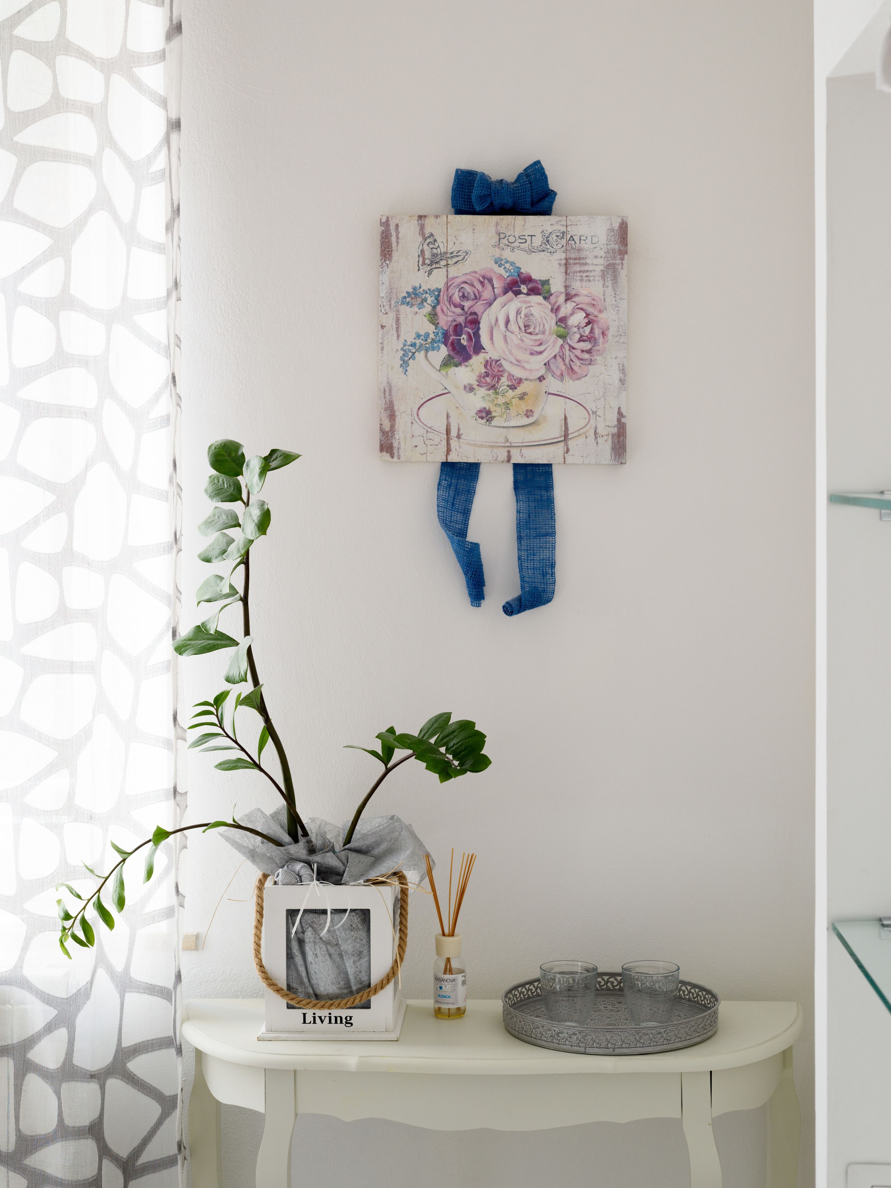 Een witte muur met een schilderij in vintage stijl van bloemen en een blauwe vlinderdas.