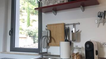 A modern kitchen with a window, stainless steel sink, red cabinets, and various kitchen items.