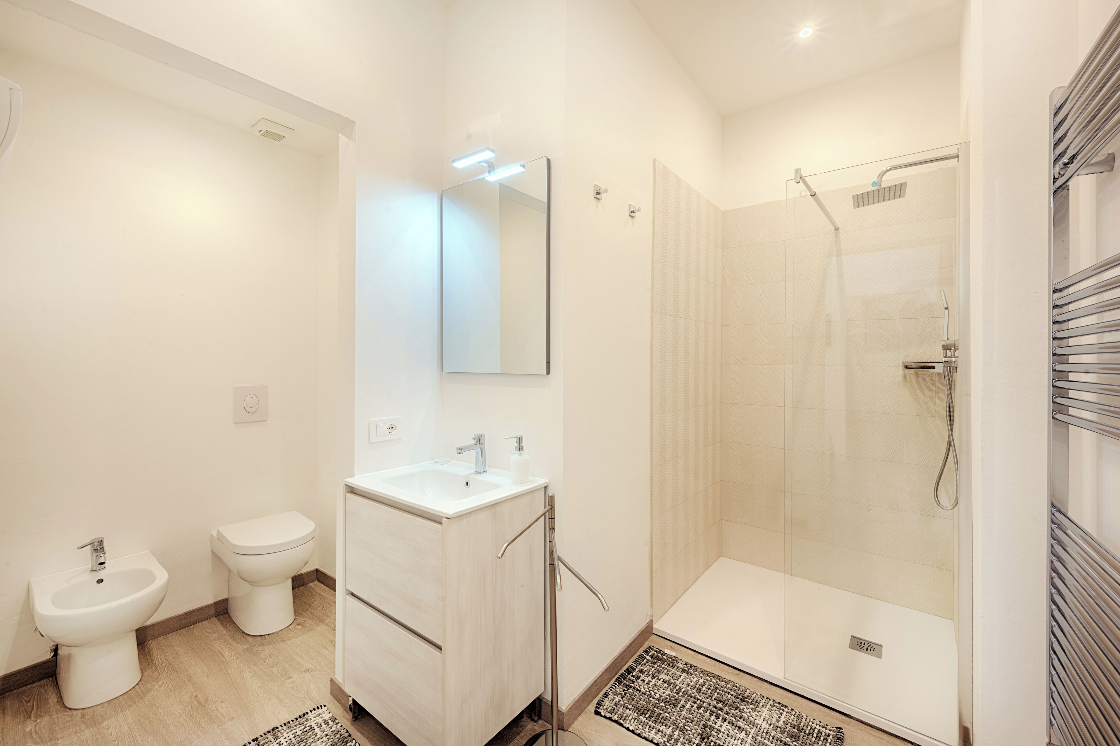 A modern bathroom with a shower, bidet, and sink.