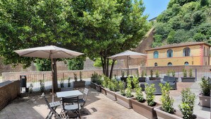An outdoor patio with tables and chairs, surrounded by planters and umbrellas.