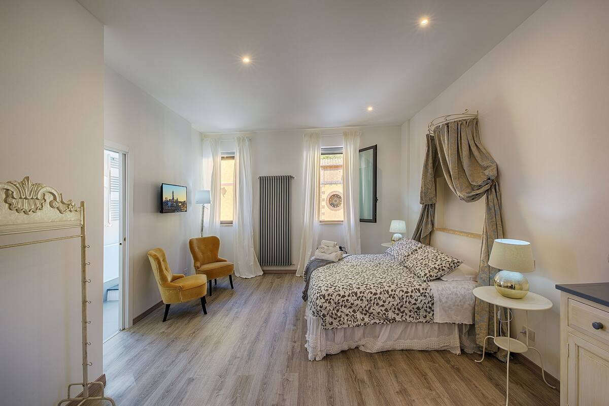 Ein Schlafzimmer mit Bett, Stuhl, Nachttisch und Heizkörper.